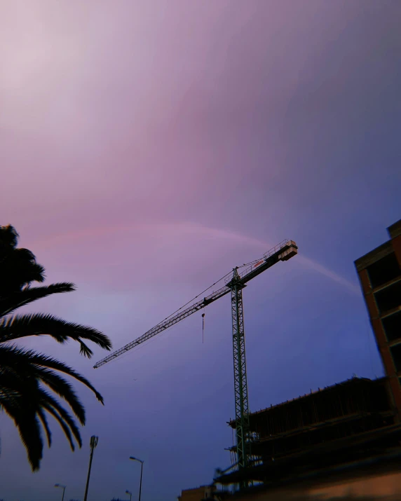 a crane at dusk under a sky that has a rainbow in it