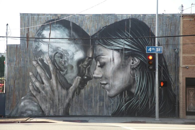 two people kissing behind a picture on the side of a wall