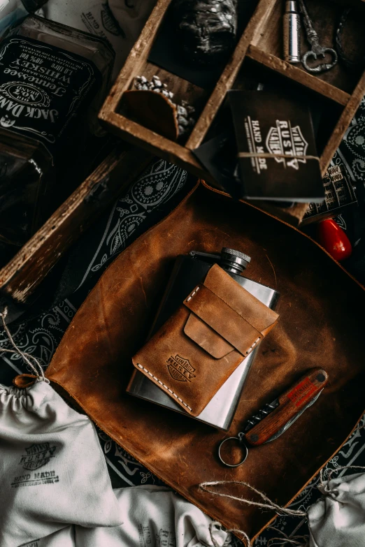 a brown leather cover, scissors and a book are on a metal tray