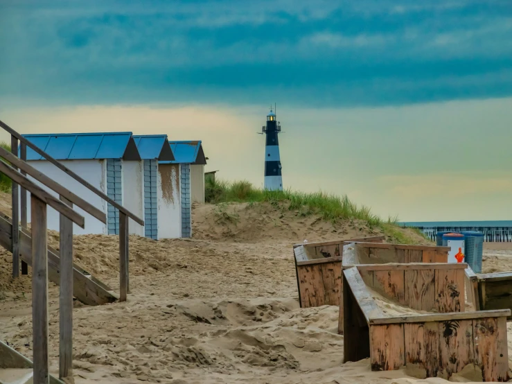 beach sand with benches, the blue and white light house in the distance