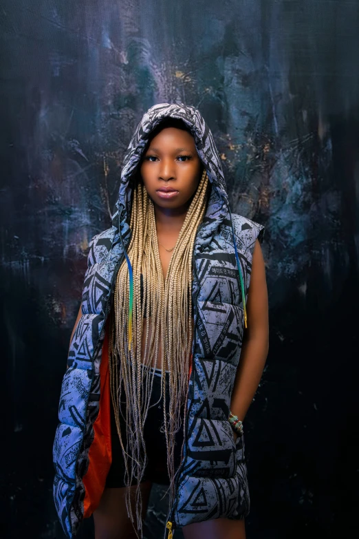 a woman wearing a hoody standing by a wall