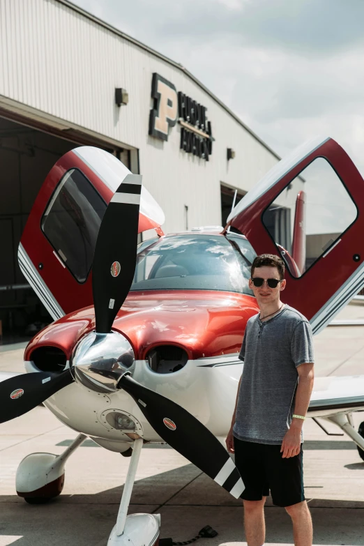 a man in sunglasses standing by a red and white plane
