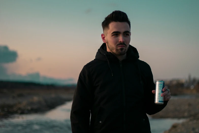 a man wearing a jacket holds a beer can in his hand