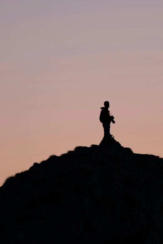 a person standing on top of a hill with the sky behind