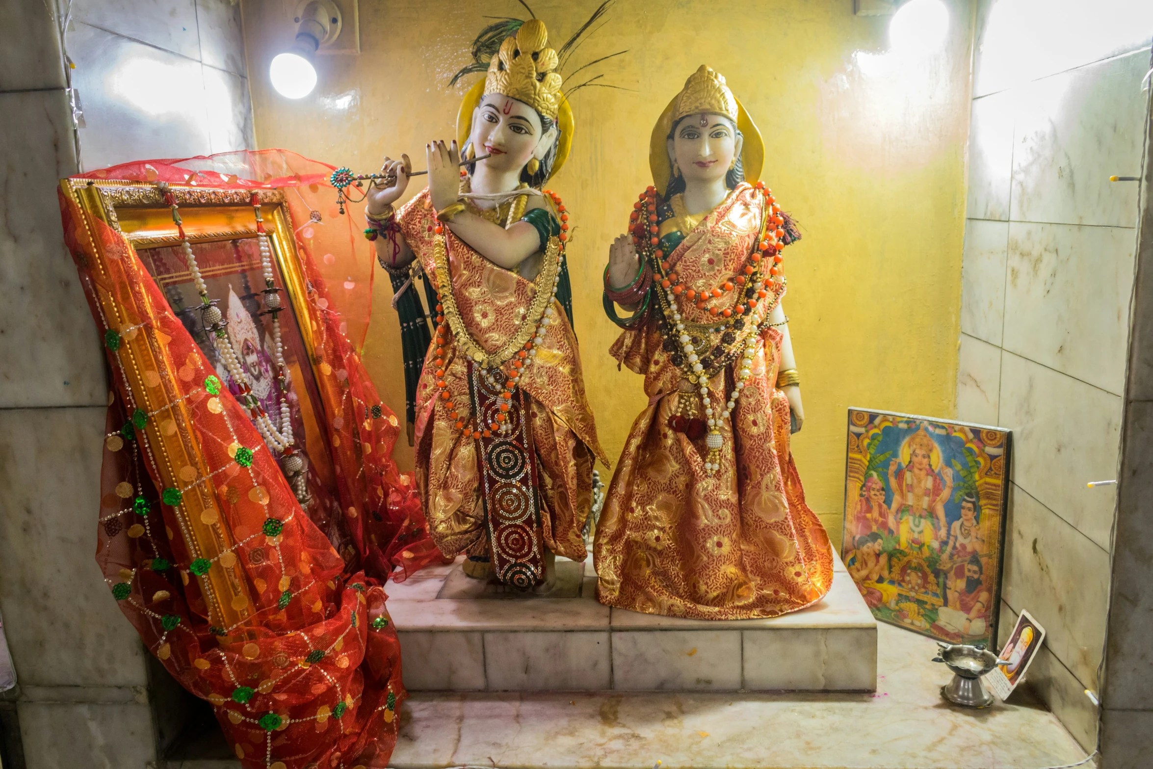 a shrine features a gold - framed mirror and three statues