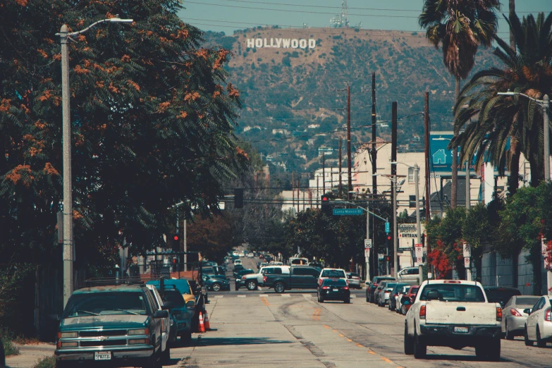 street scene with cars, a road light and a large hollywood sign