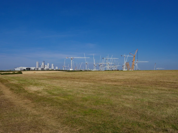 a field of dirt with cranes behind it