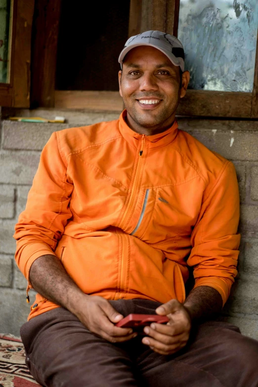 smiling man with orange shirt sitting on a bench