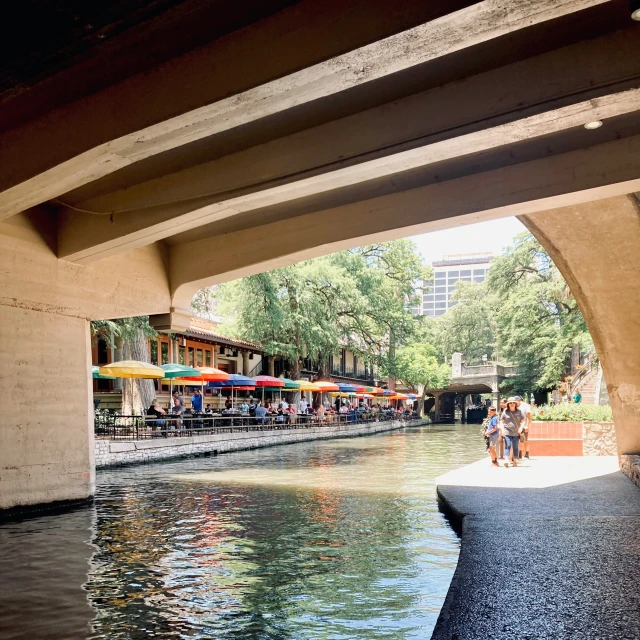 the river runs under an overpass, and a sidewalk bar is set up