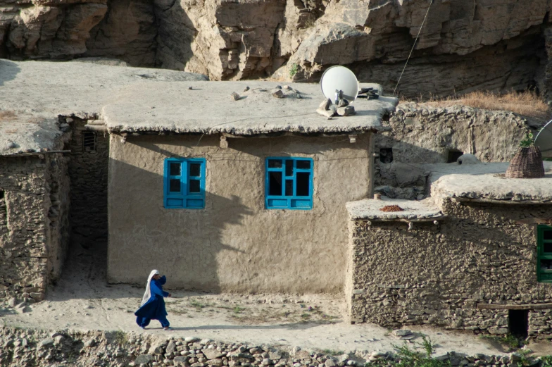 a person walking by a building on a cliff side