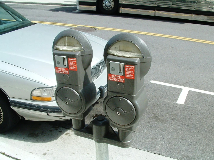 two parking meters next to a car on a street