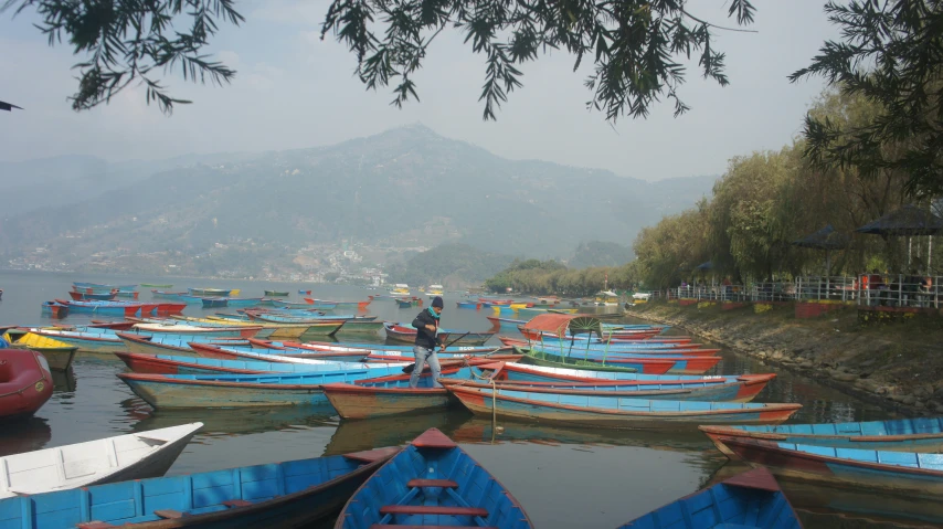 boats tied up along a shore line next to mountains