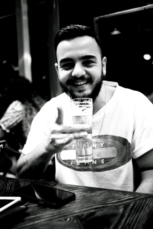 a man with a beard sitting at a table while holding up a plastic container