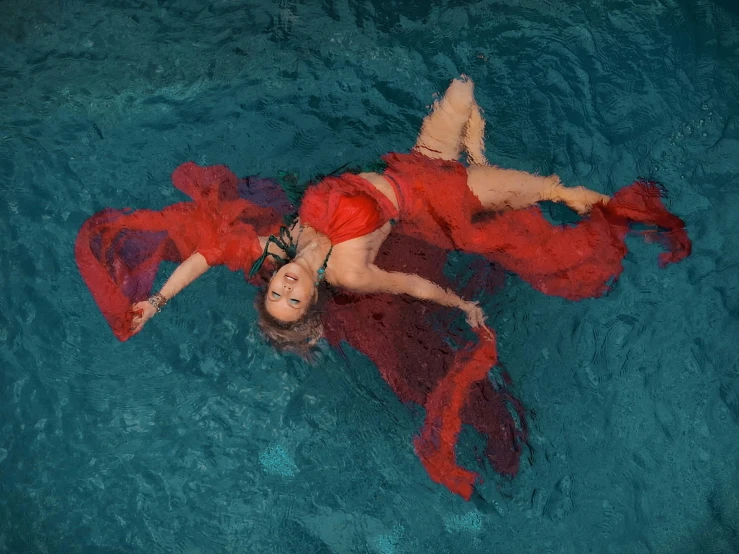 two women are floating in the water with red shawls