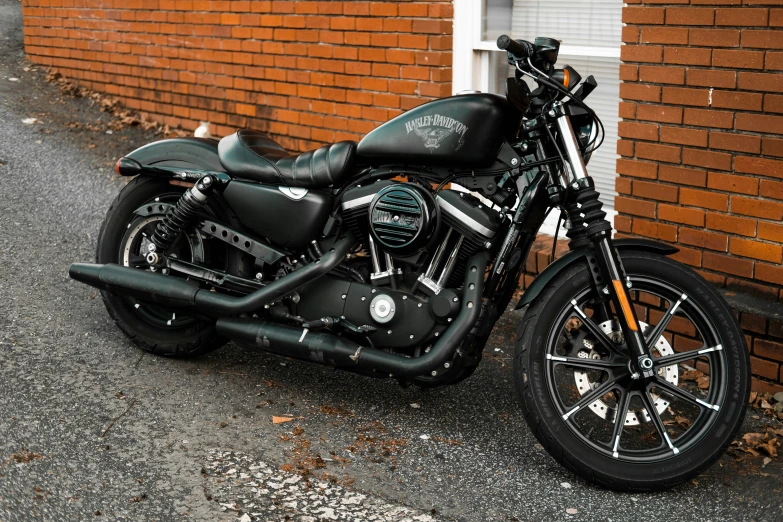 a black motorcycle parked next to a brick wall