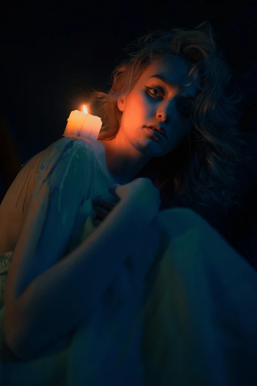 a girl sitting in bed with her hand on a lit candle