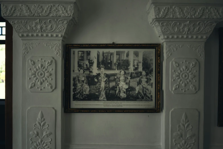 a vintage pograph hangs in a room with white stucco