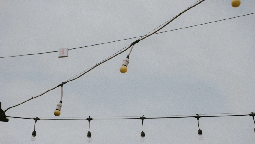 string lights hang from a wire under cloudy skies