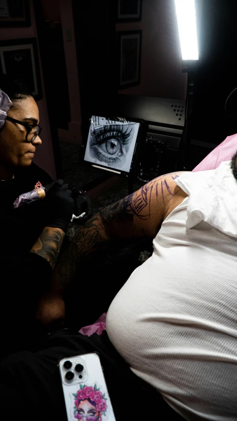 a man getting tattooed while lying down with a woman