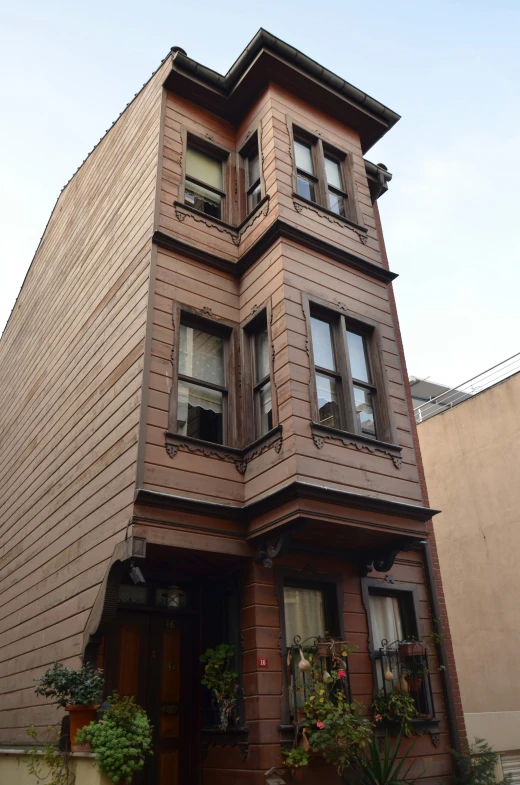 the corner of a brown house with flowers on it