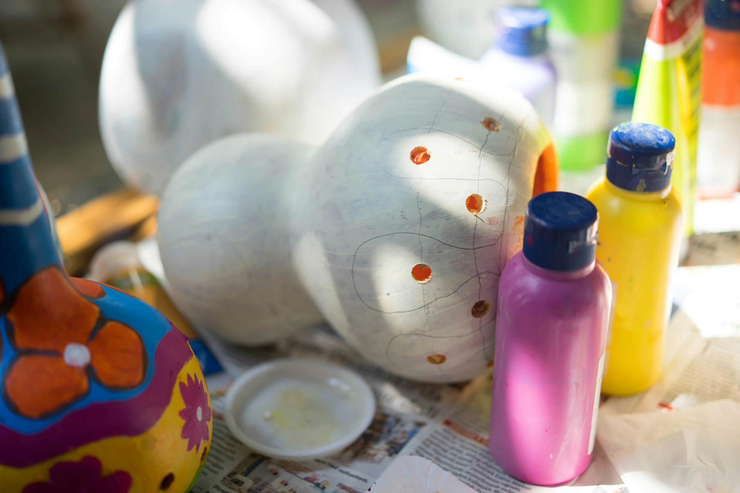 some plastic bottles and paint on top of a newspaper