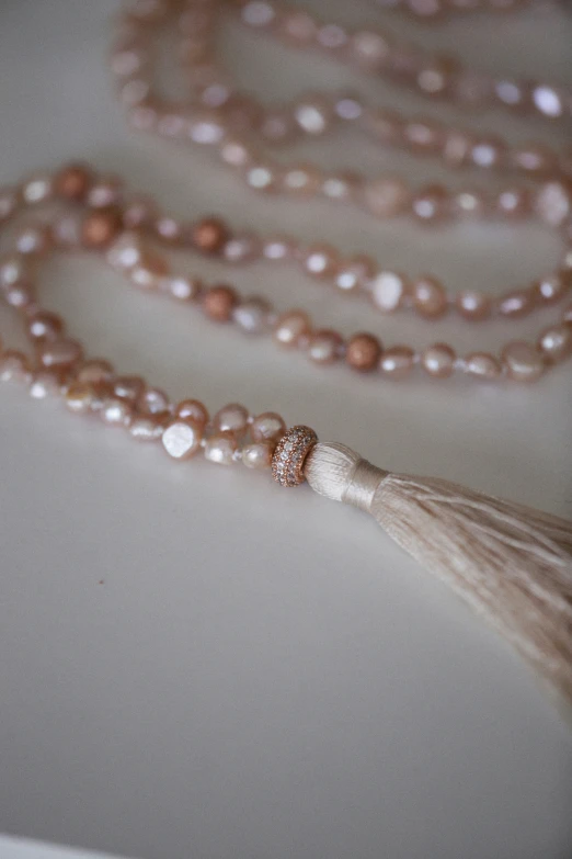 a pink long strand of pearls on a table