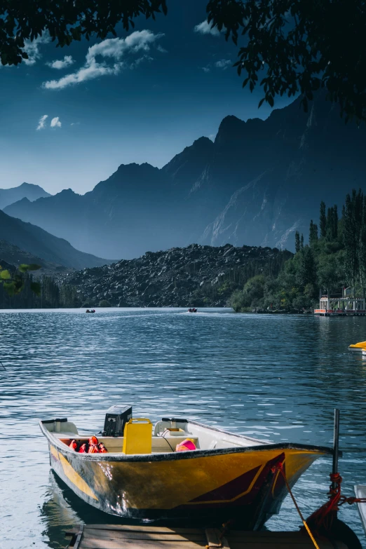 a yellow boat sitting on a lake next to a forest