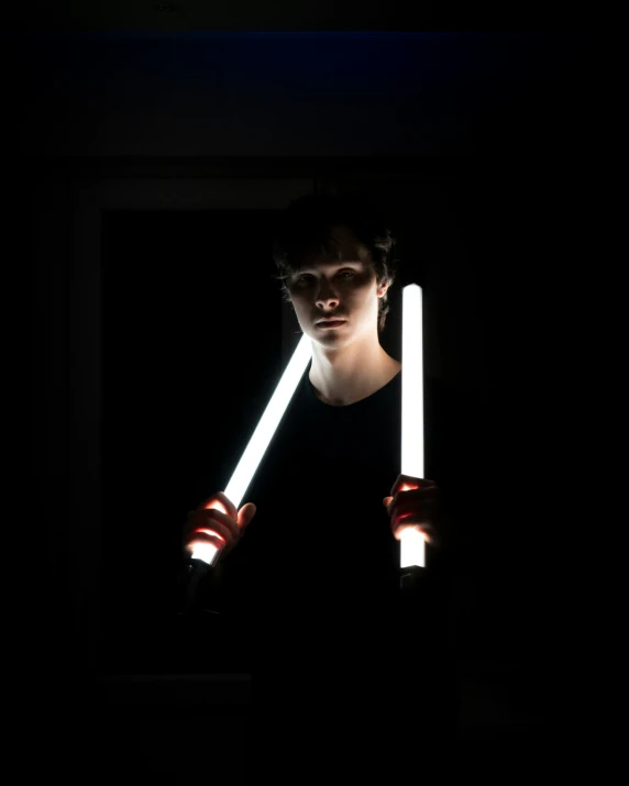 person holding two flashlights in dark room with only one lighting up