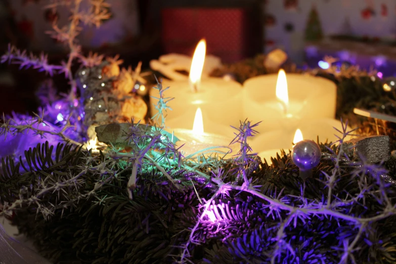 three candles lit up and decorated with lights