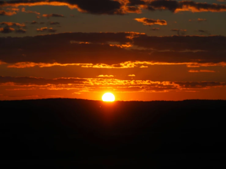 a large field with the sun setting behind it