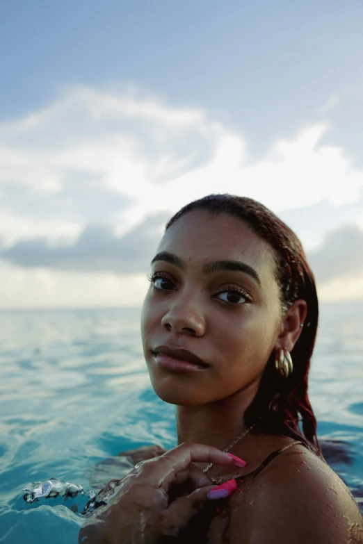 a girl with ear rings standing in the ocean water