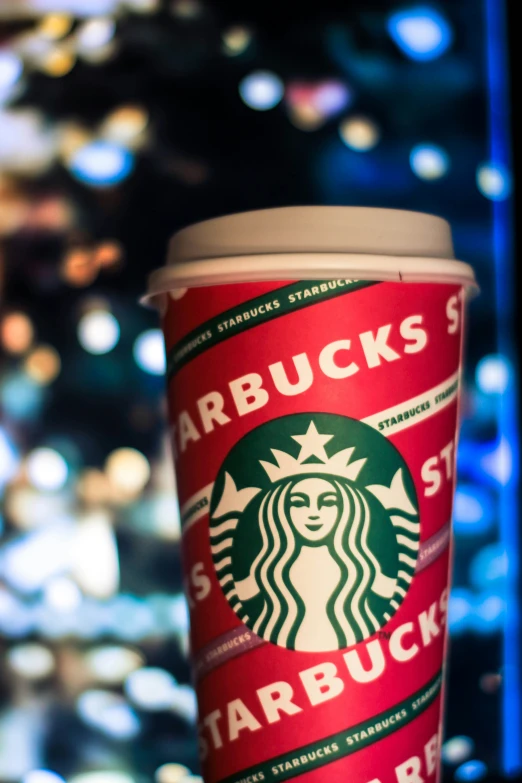 the starbucks cup is in front of some lights