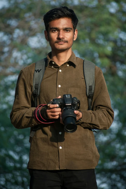a man with a backpack holds up a camera