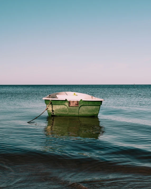 a small green boat is in the middle of water