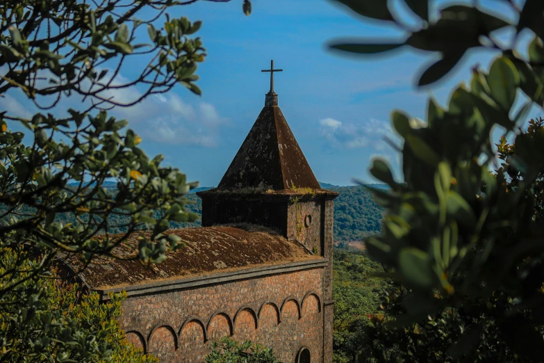 the top of a building on a hill with bushes around