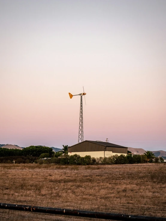 a field with an antenna on top and brown grass
