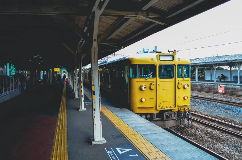 a yellow train sits at a passenger platform