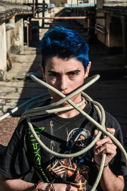 a young man with blue hair and wires hanging around his neck