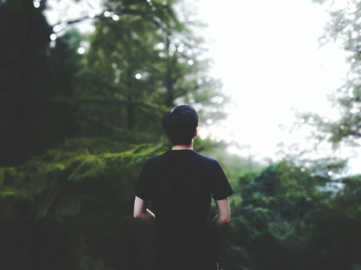 the boy is walking in the woods alone