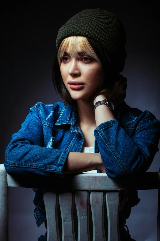 a young woman sitting on a railing with her hand on her chin