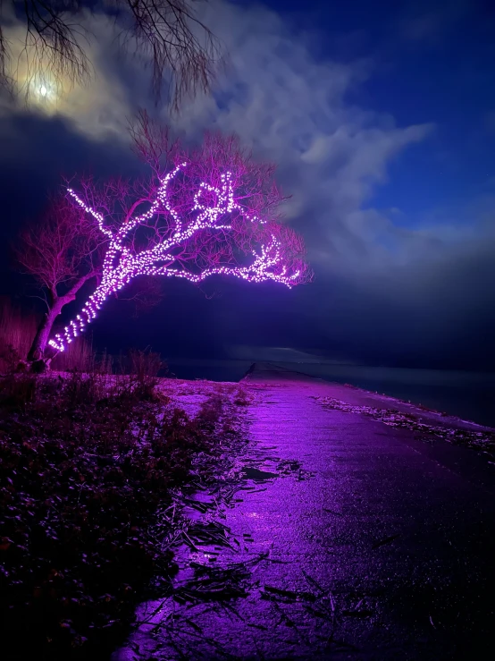a pink light shines in the night sky next to a dark road