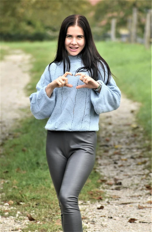 a smiling woman in grey pants with a blue sweater