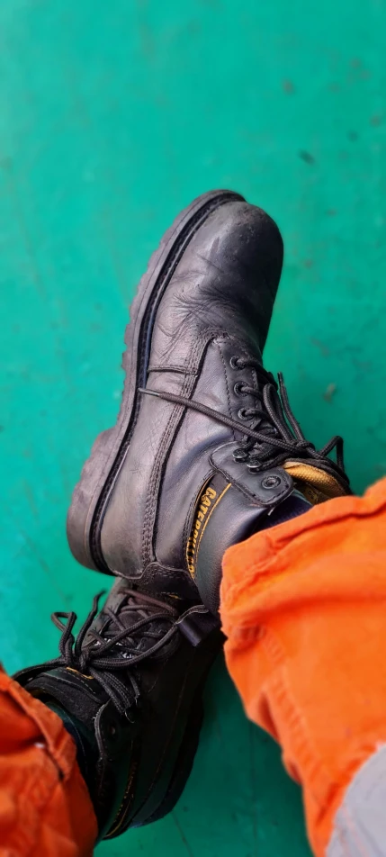 a close up of shoes on the ground with a person's legs in a pair of pants