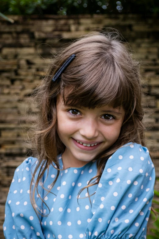 little girl with blue dress posing for camera