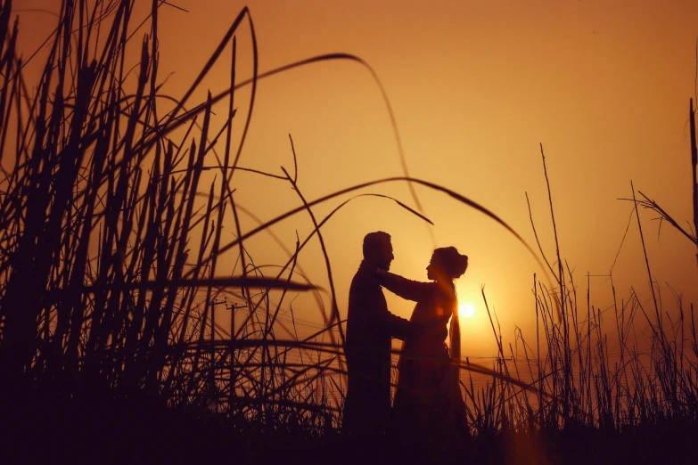 the bride and groom stand on the beach during sunset