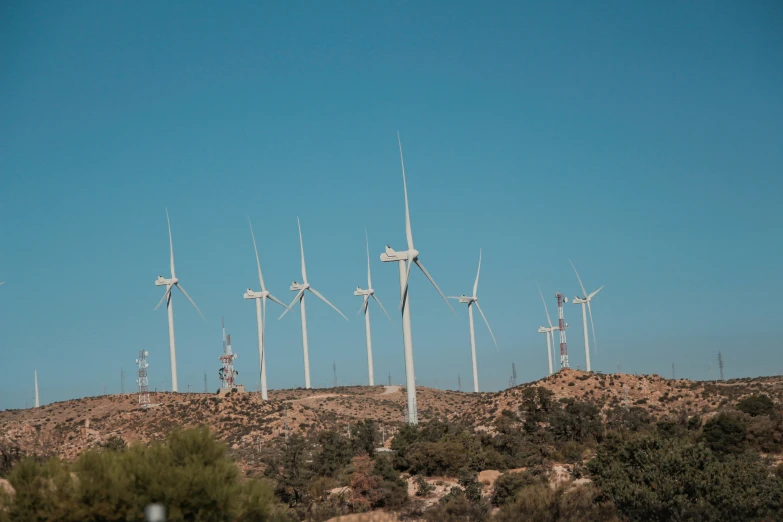 several windmills in the desert with trees around