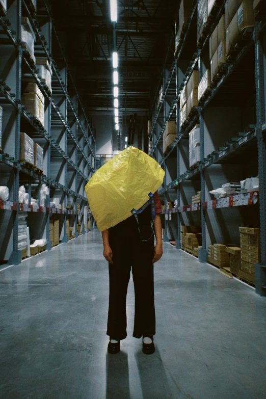 a man holding a yellow umbrella in an empty warehouse