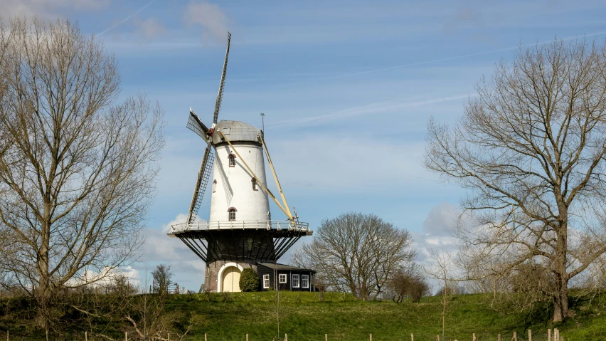 a windmill on a green hill and some trees