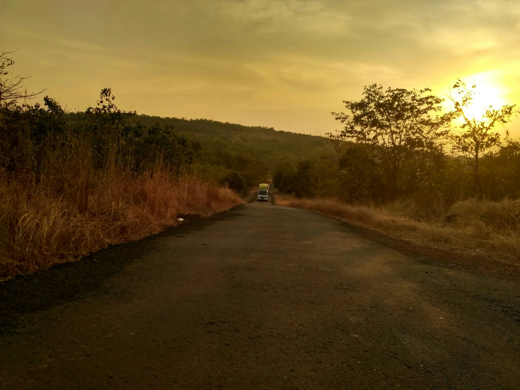 the sun sets in the distance over a deserted road