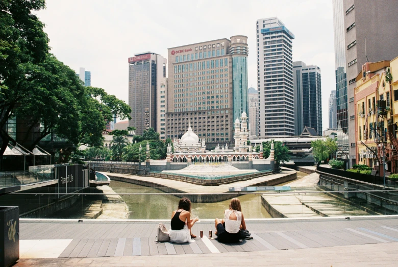 two women sitting on concrete stairs overlooking a body of water